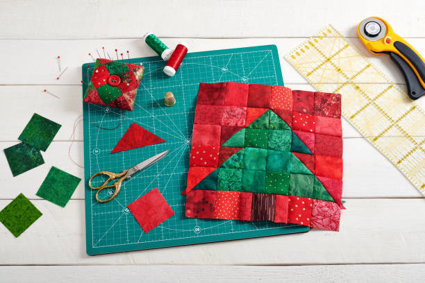 istock Christmas tree patchwork block, pieces of fabric, quilting and sewing accessories on white wooden background 1168895346