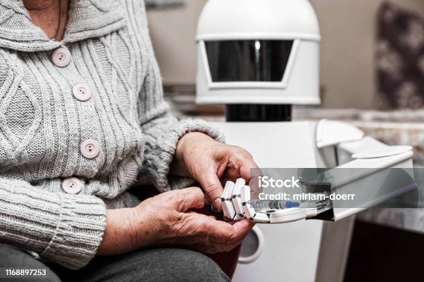 Autonomous Caregiver Robot Is Holding A Insulin Syringe Giving It To An Senior Adult Woman In Her Living Room Concept Ambient Assisted Living Stock Photo - Download Image Now