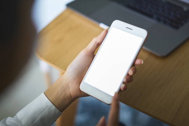 istock Hand holding smartphone with blank screen on table in cafe. Take your screen to put on advertising. 1168901704