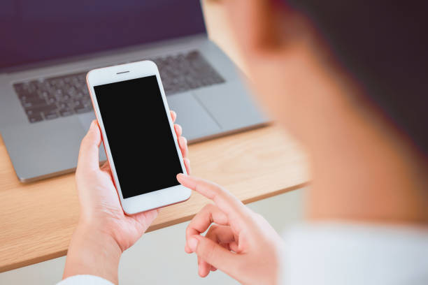 istock Hand holding smartphone with blank screen on table in cafe. Take your screen to put on advertising. 1168901833