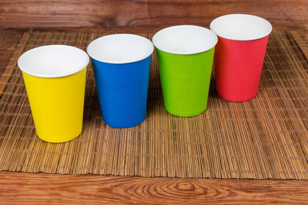 istock Disposable paper cups in different colors on bamboo table mat 1168903610