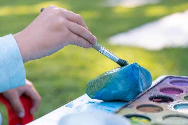 Little Toddler Boy painting on stones outdoors stock photo