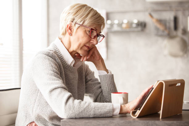 Mature woman using digital tablet at home