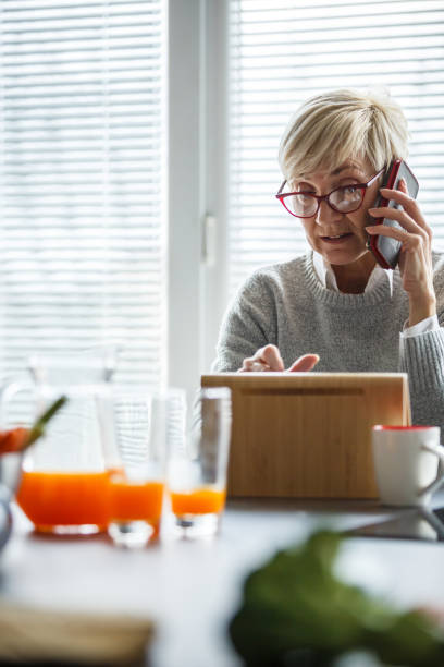 istock Woman talking on cell phone and using tablet at home 1168906948