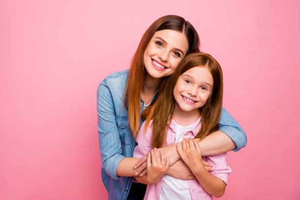 Portrait of charming ladies with long hair cuddling with beaming smile isolated over pink background Portrait of charming ladies with long, hair cuddling with beaming smile isolated over pink background little redhead girl stock pictures, royalty-free photos & images