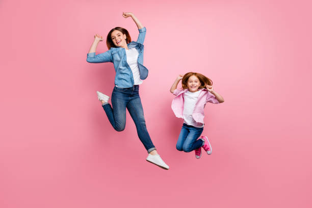 キツネの小さな女性と彼女の興奮したママジャンプハイカジュアルな服のフルサイズの写真孤立したピンクの背景 - isolated little girls two people child ストックフォトと画像