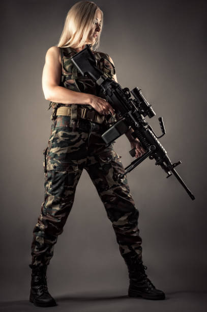 istock luxurious blonde in uniform with machine gun in hands 1168910882