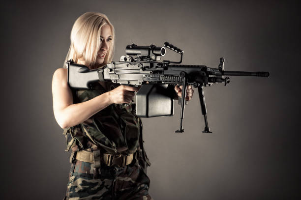 istock beautiful woman blonde aiming machine gun 1168910883