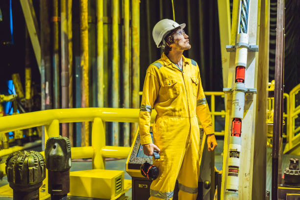 Young man in a yellow work uniform, glasses and helmet in industrial environment,oil Platform or liquefied gas plant stock photo