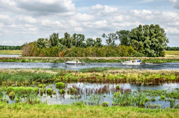 Two small yachts passing a group of trees at the new Reevediep channel near Kampen, The Netherlands, created to prevent flooding of the river IJssel