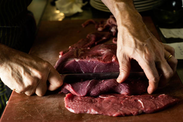 istock man cutting a piece of beef in a professional kitchen 1168926444