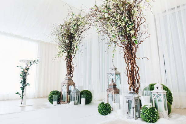 ceremonia de boda en interiores con arco de boda blanco decorado con flores y grandes velas blancas - table wedding flower bow fotografías e imágenes de stock