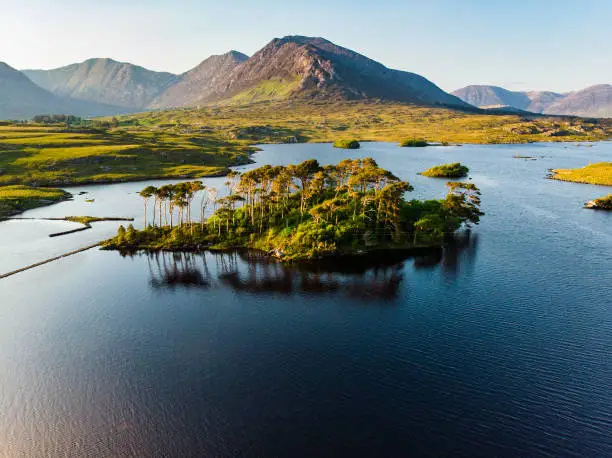 Aerial view of Twelve Pines Island, standing on a gorgeous background formed by the sharp peaks of a mountain range called Twelve Pins or Twelve Bens, Connemara, County Galway, Ireland
