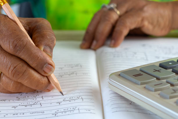 istock Close-up image of elderly asian woman hand holding pencil for compute the Maths problem using Mathematics knowledge and calculator. Education and Lifelong learning concept. 1168943644