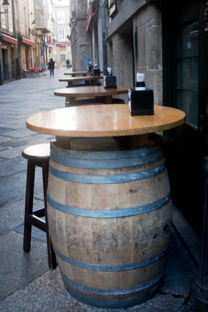 Detail of wine barrels in a row used as sidewalk cafe tables in a pedestrian zone, stool,vertical view in Ourense city, Galicia, Spain.