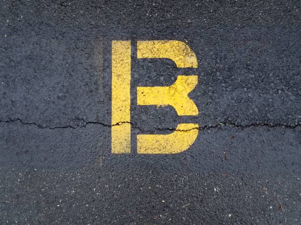 istock cracked black asphalt with yellow letter B 1168949496