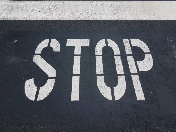 istock white stop sign painted on black asphalt street 1168949603