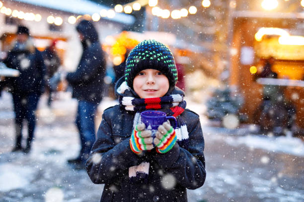 little cute kid boy drinking hot children punch or chocolate on german christmas market. happy child on traditional family market in germany, laughing boy in colorful winter clothes - hot chocolate hot drink heat drinking imagens e fotografias de stock