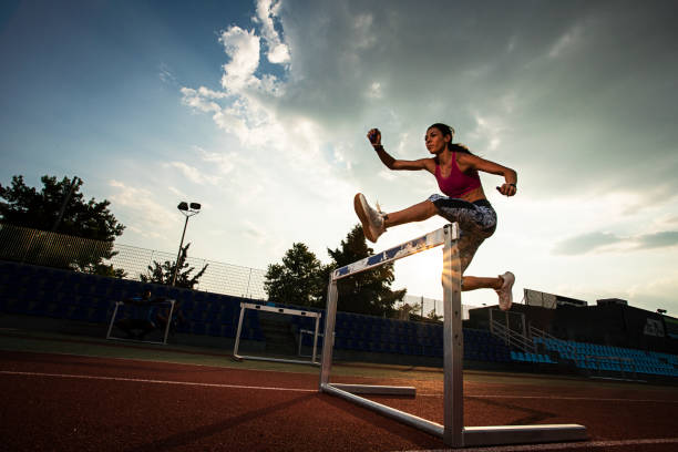 спортсменка готовит и запускает препятствия для легкой атлетики - hurdle hurdling track event women стоковые фото и изображения