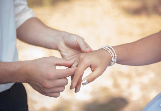 istock Couple's hands with wedding rings on yellow nature background 1168966218