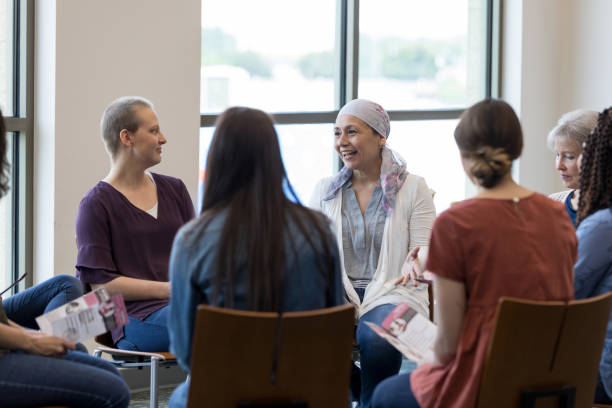 Women participating in support group Mature woman wearing a headscarf gestures while discussing chemotherapy treatment with women in a breast cancer support group. group therapy photos stock pictures, royalty-free photos & images
