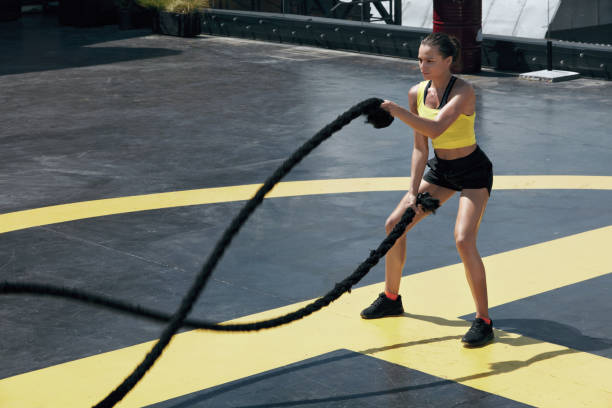 istock Sport woman doing battle ropes exercise workout at gym 1168967878