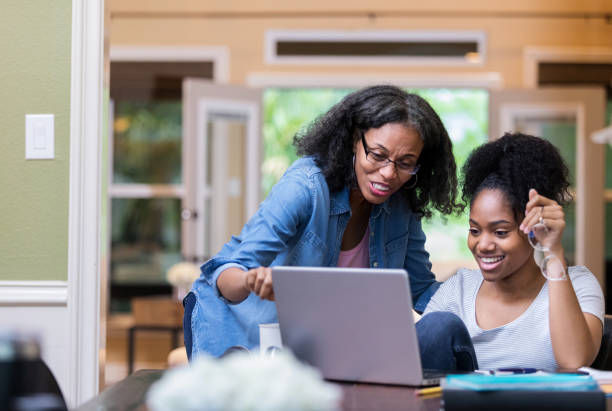 Mature mom helps her daughter study Confident mature African American mom helps her young adult daughter study for a college exam. college student and parent stock pictures, royalty-free photos & images