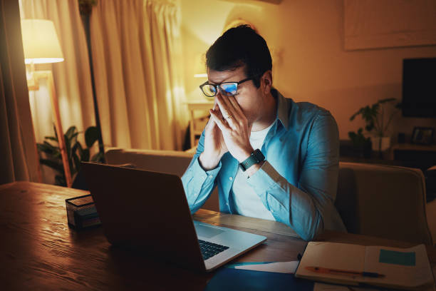 istock Exhausted man working late on laptop in night from home 1168971243