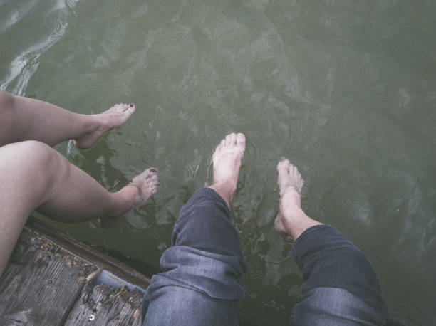 istock Man and woman legs dangling in the river 1168972999