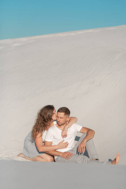 istock Romantic pair sit on white sand and huggins, in desert 1168976288
