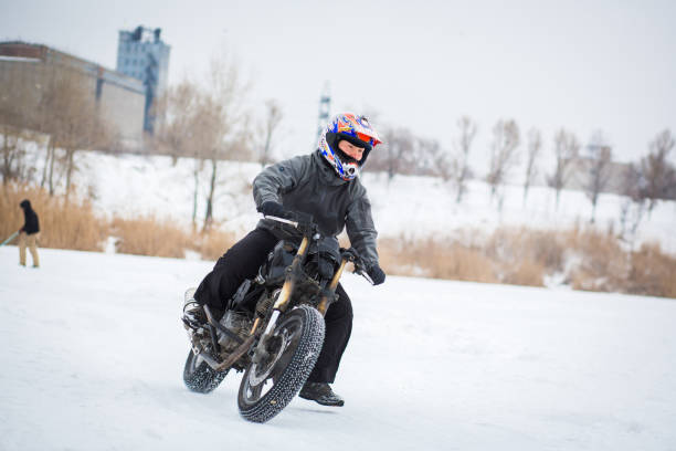 Two men lead a woman through a corner during a winter motorcycle ice race on Gull Lake in Alberta, Canada. Their tires have metal studs for grip on the snow and ice. (John Gibson Photo/GibsonPictures)