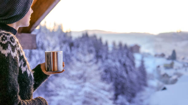 junge frau trinkt kaffee mit blick auf den winterberg - ski resort hut snow winter stock-fotos und bilder