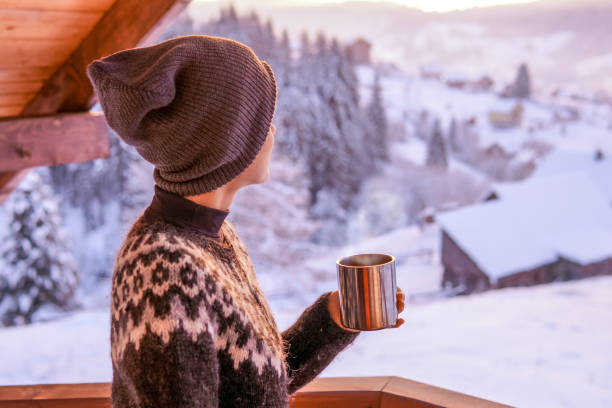 junge frau trinkt kaffee mit blick auf den winterberg - ski resort hut snow winter stock-fotos und bilder