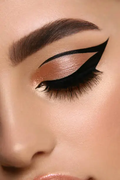 luxury female make-up close-up with eyeliner and golden eye shadow, glamourous cat eye mua, evening style