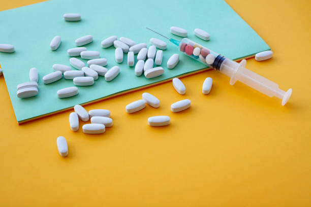 istock Syringe and pills on color background 1168982873