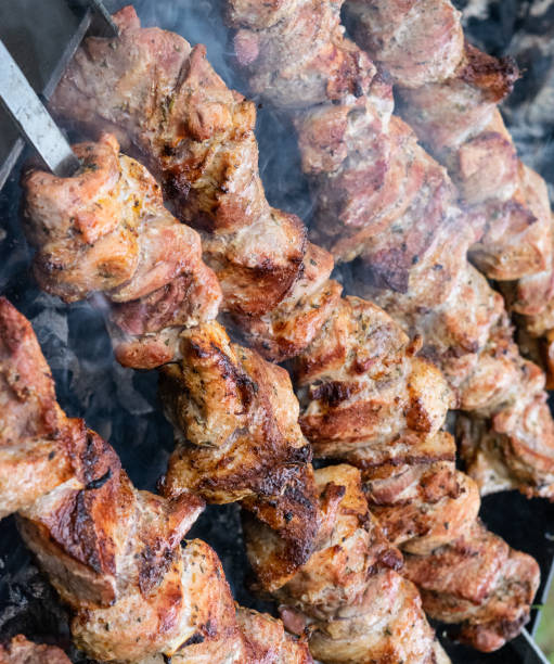 istock Frying pork on a skewer over a brazier. Turning meat over coals. Appetizing shish kebab. 1168986134