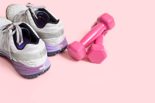istock Sneakers with dumbbells on a pink Surface 1168991727