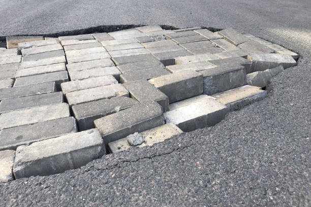 istock Road repair concept. Pit with a brick in an asphalt road 1168992075