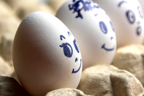 istock Lovely eggs in cardboard box. Eggs with emotions. White eggs in cardboard box with different faces painted on them. Boys and girl 1168992166