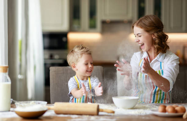 famille heureuse dans la cuisine. mère et enfant préparant la pâte, cuire des biscuits - rolling dough pastry apron photos et images de collection
