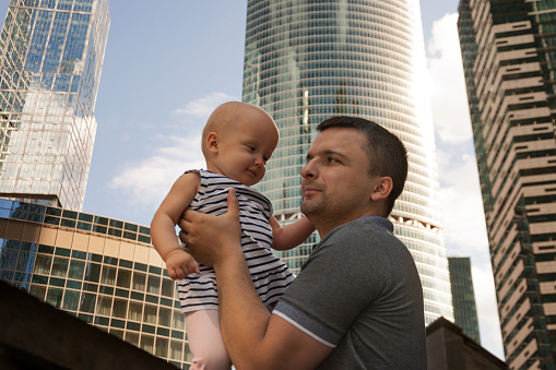 Father and one year old daughter against the sky and skyscrapers. Travel with children, the development of emotional intelligence. Early development