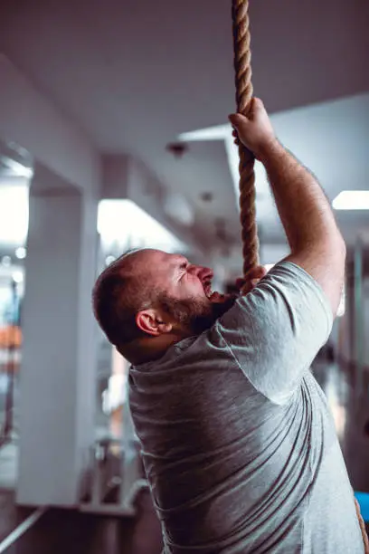 Photo of Overweight Male Giving His Best To Compete Rope Climbing Exercise