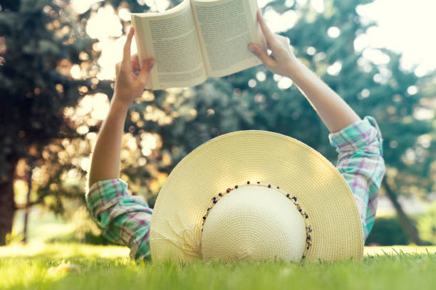 istock Young Girl Lying on Grass and Reading Book. 1169000257