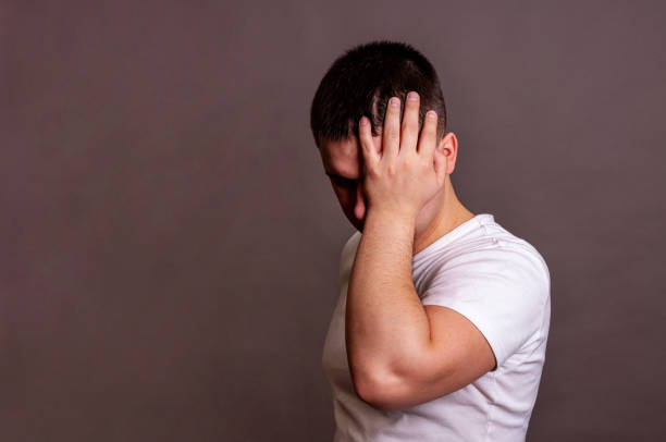 istock Headache. A young guy in a white T-shirt holding his head. 1169000462