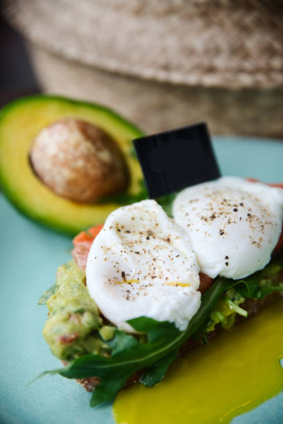 istock Hot toast with salmon, poached egg, herbs and avocado on a plate with a black copy space flag on a skewer 1169007498