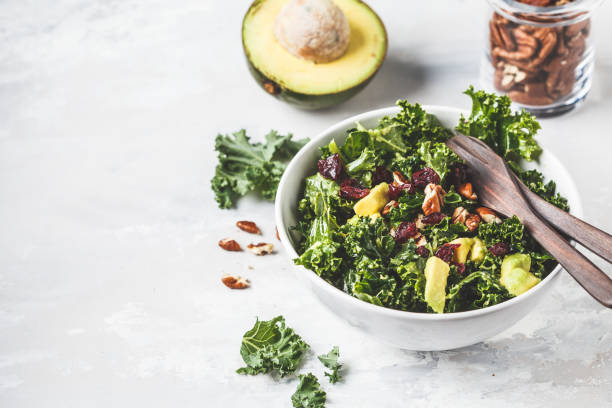 ensalada de col rizada verde con arándanos y aguacate en tazón blanco. concepto de comida vegana saludable. - cabbage close up food fork fotografías e imágenes de stock