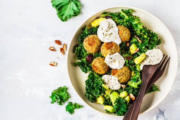 Vegan lentils meatballs with green kale salad, avocado and tahini dressing in a white dish, top view. stock photo