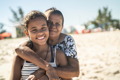 Portrait of grandmother and granddaughter embracing in the beach