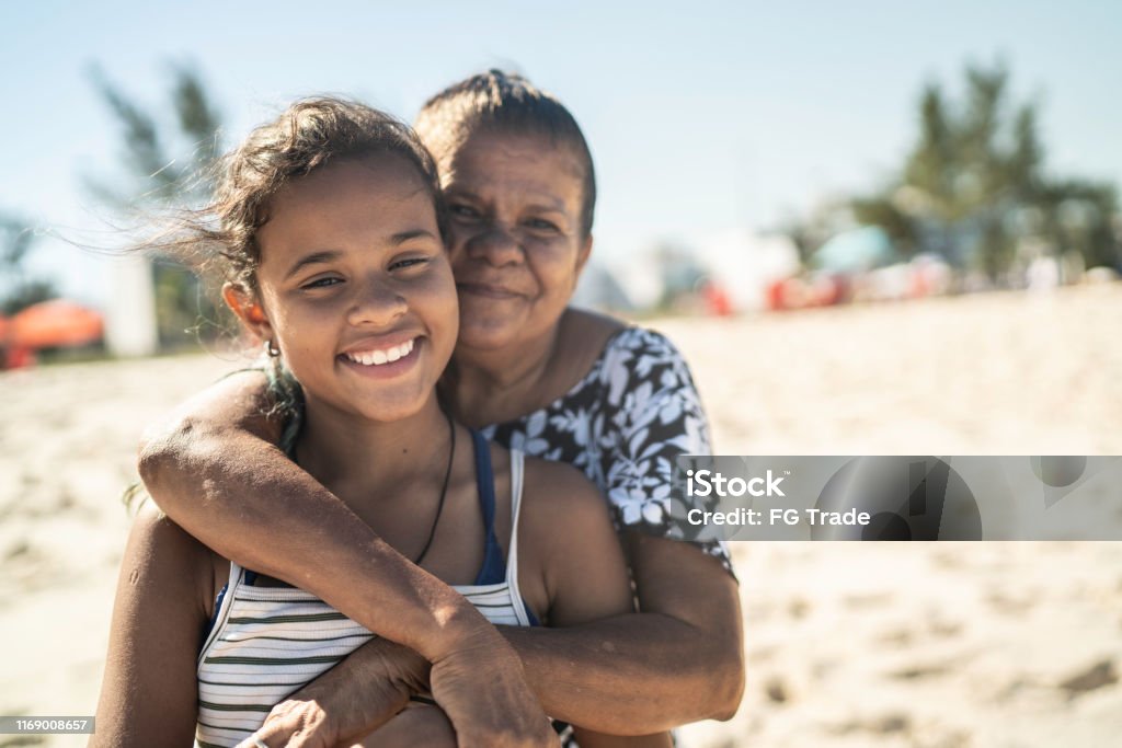Portrait of grandmother and granddaughter embracing in the beach Teenager Stock Photo