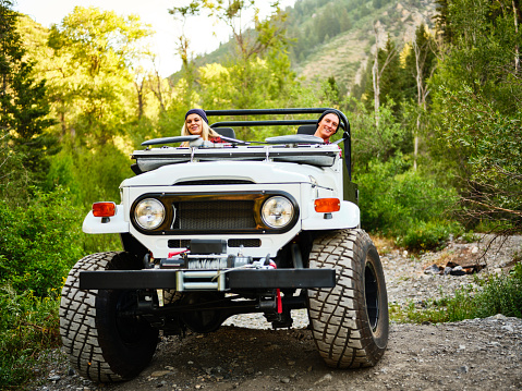 A young couple driving an off road 4x4 vehicle in a wilderness area.